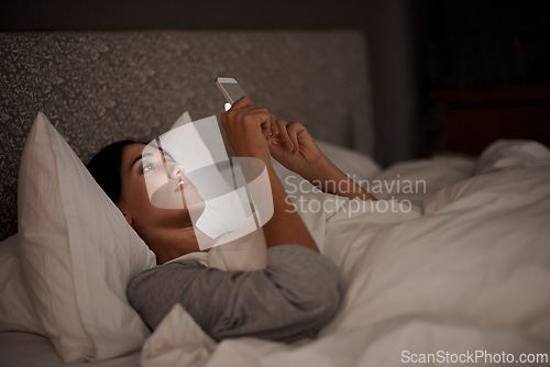 Image of Woman, scrolling and phone for social media, bed and relaxation under blankets in pajamas to sleep. Female person, browse and tech for peace, night and online for conversation, chat and memes