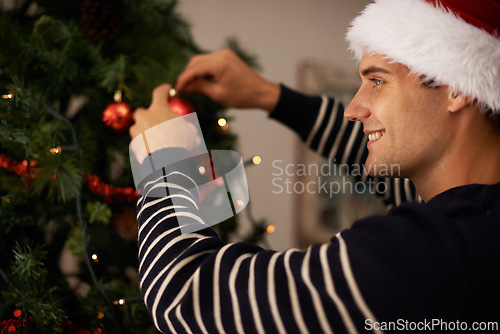 Image of Living room, house and man with smile for decorations on tree for Christmas party or celebration. Apartment, happiness and male person with joy in family home for tradition and vacation for holiday