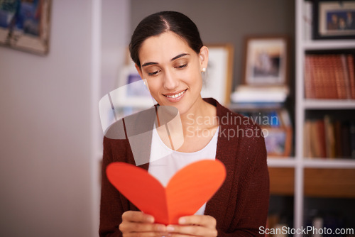 Image of Woman, reading and heart letter in home for valentines day, memory and happy for celebration with sign. Girl, person and greeting card for love, kindness and note for relationship with smile in house