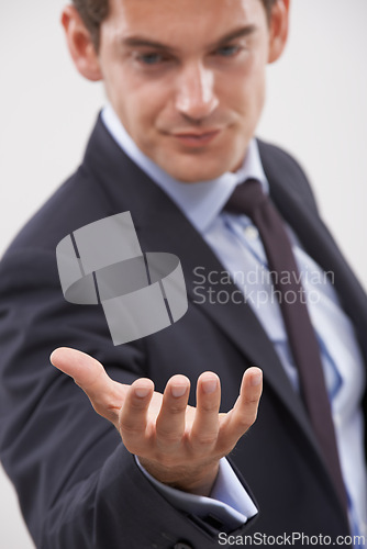 Image of Businessman, palm and hand with interaction for hologram or virtual display on a gray studio background. Isolated young man, user or business employee showing gesture sign, symbol or 3D technology