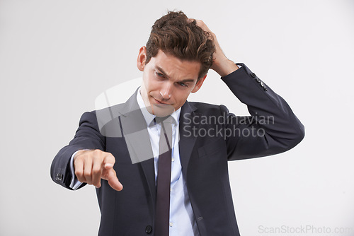 Image of Businessman, confused and pointing with touch, UX or UI display on a gray background. Young man, user or employee in doubt with finger or interaction for virtual technology, push or click on mockup