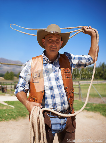 Image of Cowboy, ranch and lasso in outdoor, sun and straps for wrangler and Texas farmer at stable. Mature man, wild west and summer in agriculture, hat and male person with rope in farm job and environment