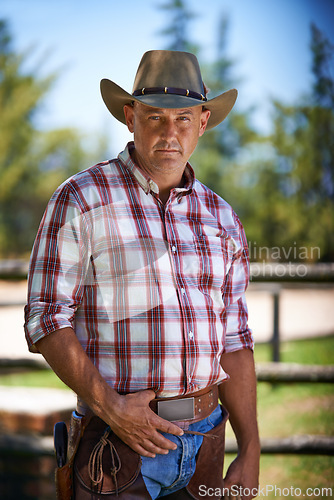 Image of Portrait, serious cowboy and man at farm in the rural countryside for agriculture in Texas. Ranch, confidence and male person in western hat outdoor in casual clothes in nature at stable on field