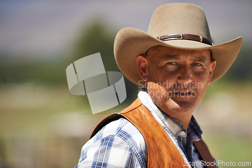 Image of Portrait, confident cowboy and man at farm in the rural countryside for agriculture in Texas. Rancher, serious and face of male person in western hat outdoor in casual clothes in nature at stable