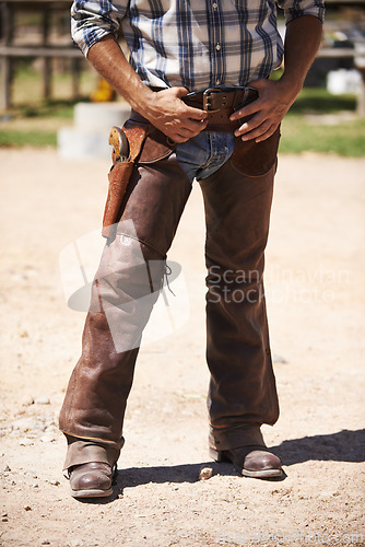 Image of Farm, nature and legs of cowboy on ranch with weapon for horse, cows and rodeo animals for agriculture. Farming, costume and closeup of man in environment, countryside and working outdoors in Texas