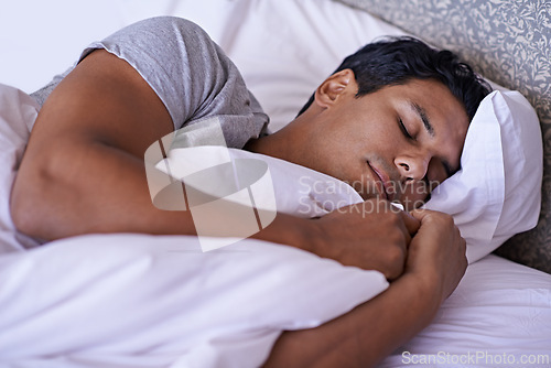 Image of Man, tired and sleeping in bedroom in morning, quiet and peace rest on soft pillow in warm duvet. Calm person, dream and relax on bed in white bedding, fatigue and wellness on lazy weekend in home