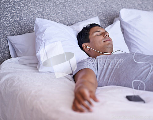 Image of Man, music or sleeping in bed in morning, tired or peace with audio podcast or audiobook on soft mattress. Calm person, dream or relax by cellphone for online meditation, happy or listening to radio