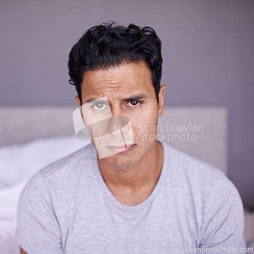 Image of Man, sad and frustrated in bedroom in portrait, disappointment and upset with mental health in morning. Young person, unhappy face and problem on weekend with depression and grumpy on bed in house
