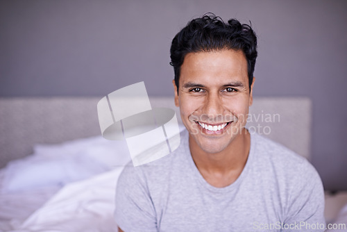 Image of Man, happy and relax in bedroom in portrait, wellness and confident on morning vacation on home. Young person, smile face and healthy on break on lazy weekend, pyjamas and calm on bed in apartment