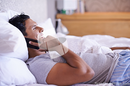 Image of Bed, smile or phone call with a happy man to relax in communication, morning or connection. House, wake up and male person resting in home talking on a mobile for news, listening and conversation