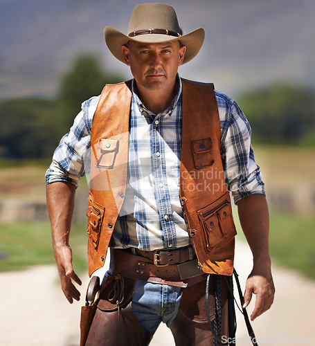 Image of Portrait, serious cowboy and man at farm in the rural countryside to draw gun in Texas. Ranch, confidence and male person in western hat outdoor in casual clothes in nature with pistol or revolver