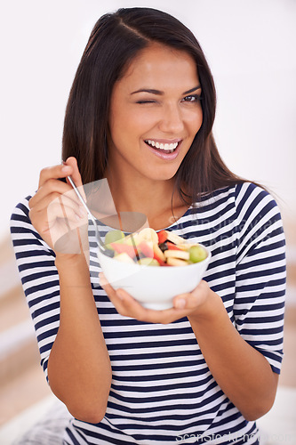 Image of Fruit, portrait and wink with healthy eating woman, bowl and happy for fresh food. Natural, nutrition and sustainable for vegetarian, fiber and breakfast or dessert for minerals and vitamins