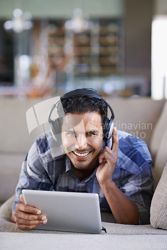 Image of Man, headphones and tablet for music or website, home and internet for streaming. Happy male person, relax and song app on couch for audio or podcast, smile and online for blog or subscription
