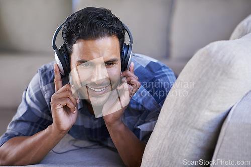 Image of Man, headphones and listening to song on couch, relax and streaming radio for music or sound. Happy male person, home and lying on sofa for peace, comfortable and hearing jazz playlist on weekend