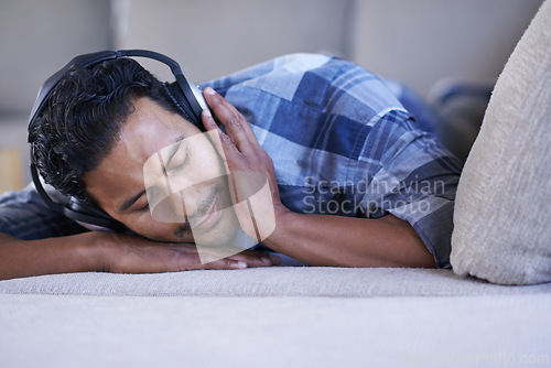 Image of Man, headphones and relax with song on couch, nap and streaming radio for music or sound. Male person, home and lying on sofa for peace, comfortable and calm playlist on weekend for sleep or meditate