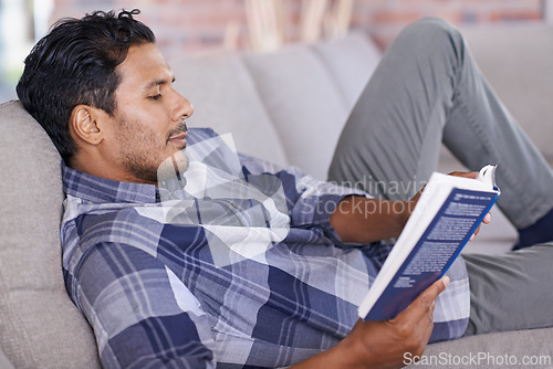 Image of Man, relax and couch with book for reading for information or knowledge, development and quiet time for comfort. Male person, leisure and literature novel for learning or contentment and inspiration.