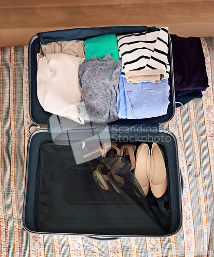 Image of Travel, luggage and clothes in suitcase for holiday or vacation packing in bedroom from above. Adventure, bag and journey with clothing on bed in apartment, hotel or lodge for weekend getaway