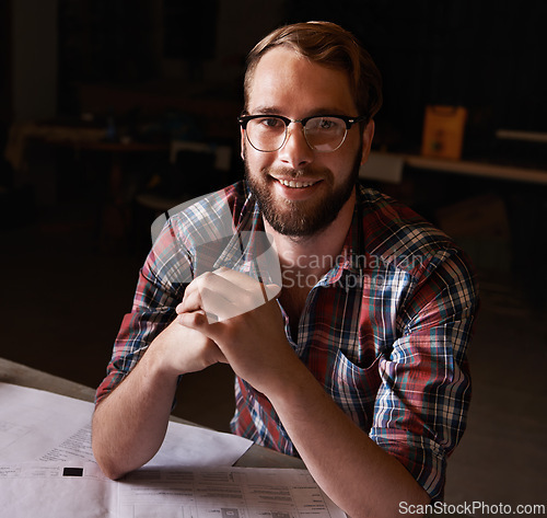Image of Portrait, man and architect with documents in workshop on wooden table for paperwork of startup. Confident, entrepreneur and male person with smile for small business in industry for construction