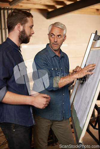 Image of Carpenter, team and men with blueprint for planning, construction or building. Engineer, apprentice and mentor with design, drawing and senior father teaching serious son in discussion at workshop