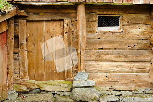 Image of Rustic wooden barn wall with weathered door and stone foundation