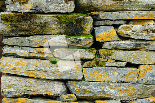 Image of Time-worn stone wall clad in moss and lichens, a testament to na