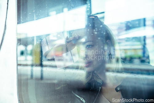 Image of Woman traveler contemplating outdoor view from window of train. Young lady on commute travel to work sitting in bus or train.