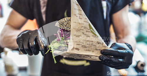 Image of Chef serving vegetarian salmon burgers outdoor on open kitchen, odprta kuhna, international food festival event. Street food being served on a food stall.