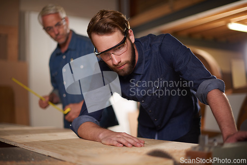 Image of Carpenter, team and man with wood saw for planning construction project or senior father teaching son. Machine apprentice and mentor in woodwork, training and learning at workshop with plank on table