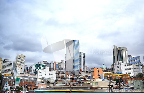 Image of Cityscape, skyline and buildings in urban architecture with development, expansion and clouds in town. City, metro and skyscraper on road, fog or winter morning on location with dark sky in Sao Paulo