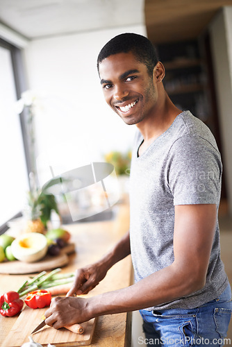 Image of African, man and kitchen cooking and chopping, smiling and relaxed happy morning at counter. Confident and male person, food and culinary in apartment, nutrition and organic vegetable for breakfast