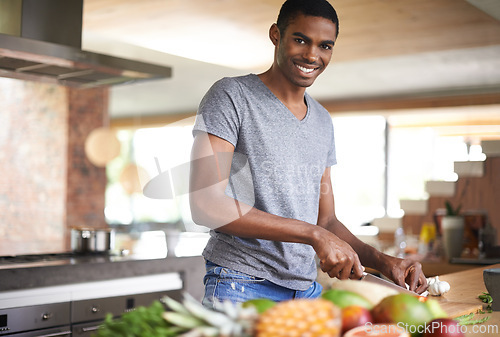 Image of Man, fruit and vegetables with knife in portrait for cooking, salad and happy in home kitchen. African person, smile and pride with food, nutrition and vegan diet for health, wellness and meal prep