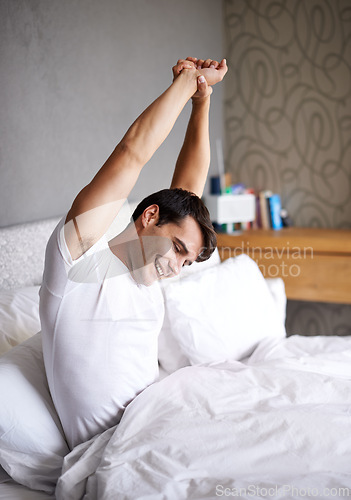 Image of Male person, morning and stretch in bed, house and smile for daily routine and pajamas for rest and wellness. Man, happy and bedroom indoor, and home in waking up and relaxing on Saturday day off
