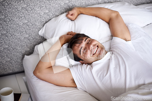 Image of Man, sleep and bed for stretch, wellness and happy for rest in pajamas and bedroom for home and joyful. Male person, relax and dreaming at house, calm and tired in sleepwear and taking nap and smile