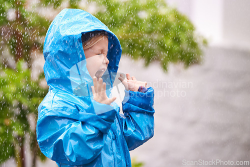 Image of Young girl, rain and playing outside in winter, raincoat and playful in the water. Joyful, laughing and happy child in cold weather and raindrops, screaming toddler and excited in backyard of home