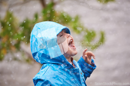 Image of Boy, jacket and rain in winter with playing for fun, carefree childhood and happiness with freedom. Child, excited and smile with mouth open in nature for vacation, weekend or holiday in cold weather