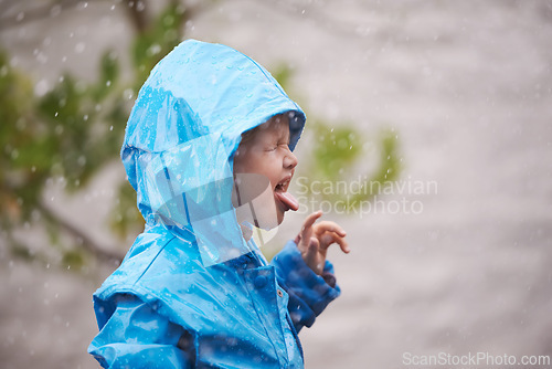 Image of Boy, rain jacket and playing in winter with happiness, fun and carefree childhood in cold weather. Young child, tongue out and water in nature for vacation, holiday and weekend enjoyment in Australia