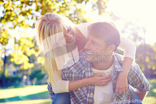 Image of Couple, smile and park piggyback for love together on vacation or nature explore, sunshine or relax. Man, woman and face for holiday in environment for relationship happiness, summer or adventure