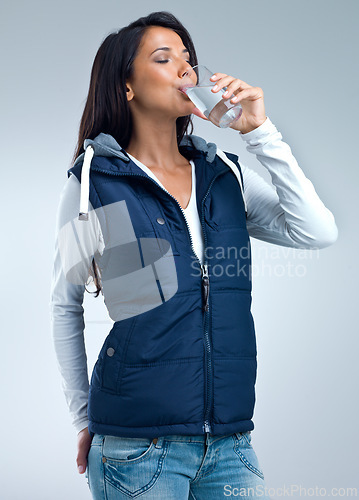 Image of Woman, drinking water for health and hydration in studio, nutrition and wellness with thirst on grey background. Liquid, aqua and mineral with h2o in glass, fresh and clean for refreshment and detox