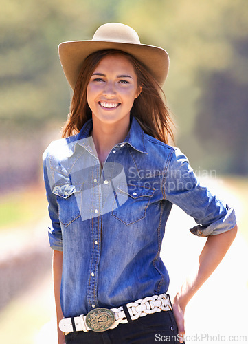 Image of Happy woman, portrait and cowgirl with hat on farm for adventure, travel or outdoor journey in Texas. Female person with smile in western fashion, denim shirt and cap at ranch in the countryside