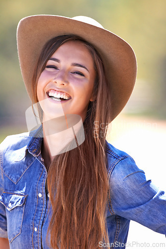 Image of Portrait, fashion and smile of cowgirl on farm or ranch for agriculture or sustainability in summer. Countryside, texas or western with happy young person in hat outdoor in field for organic farming