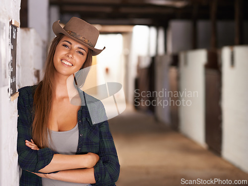 Image of Portrait, smile and arms crossed with cowgirl in barn of farm for agriculture, equestrian or sustainability. Countryside, rural or western with happy young person at ranch in countryside for farming