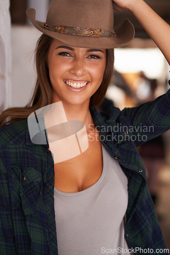 Image of Portrait, smile and confident with cowgirl in barn of farm for agriculture, equestrian or sustainability. Countryside, rural or western with face of happy young person at ranch in countryside