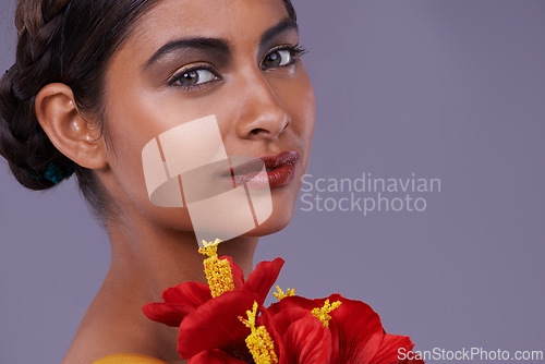 Image of Portrait, beauty and woman with flowers for skincare, makeup or mockup isolated on a purple studio background in India. Face, model and cosmetics with bouquet for natural skin with organic hibiscus