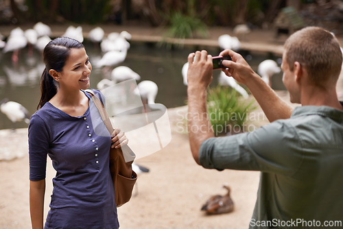 Image of Picture, park and couple with love, date and memory with digital app and vacation for honeymoon. Outdoor, man and woman with smartphone and post with getaway trip and sanctuary for birds with smile