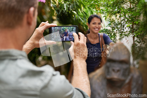 Image of Picture, park and couple with screen, date and memory with digital app and vacation for anniversary. Outdoor, man or woman with cellphone or post with getaway trip or sanctuary for animals with smile