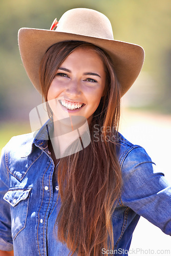 Image of Happy woman, portrait and cowgirl with hat for nature adventure, travel or outdoor journey in Texas. Young female person with smile in western fashion, denim shirt and cap at ranch in the countryside
