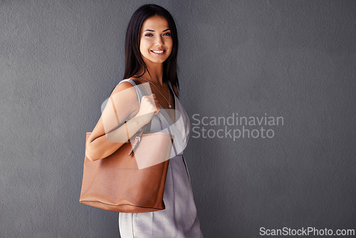 Image of Studio, portrait and handbag with fashion, joy and accessories with dress and smile. Woman, face and model with confidence, beauty and happiness with purse and style isolated on gray wall background