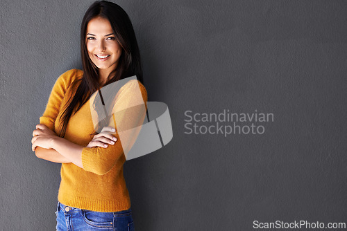 Image of Portrait, arms crossed and woman in studio, fashion or cool style in gray background. Female person, smile and happy with confidence in mockup space, stylish and edgy in casual outfit or clothes