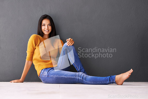 Image of Portrait, woman and relax or style on floor with casual outfit for fashion or comfort, leisure and wellness with smile. Female person, isolated with grey background or wall for clothing with mockup