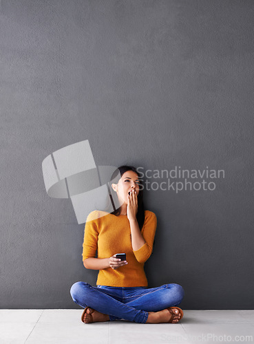 Image of Bored, tired or woman with phone yawn on floor for social media, scroll or web search on wall background. Fatigue, burnout or female person with smartphone app on the ground sleepy from reading ebook